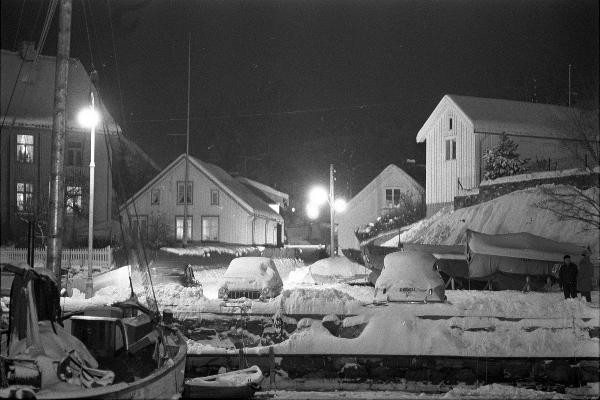 Bevaring av "det gamle Drøbak", Frogn, februar 1970. Vinterbilde havn med fiskebåt, nedsnødde biler og boliger. Trehusbebyggelse.