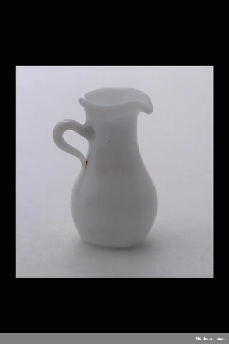 Inventering Sesam 1996-1999:
H  2,5 (cm)
Handkanna, till dockskåp, av opalglas, hög, med bukig nederdel.
Tillhör dockskåp inv.nr 193.059. Skåpet är ritat år 1880 av givarinnans far, som lät en snickare tillverka det.
Anna Womack okt 1997
