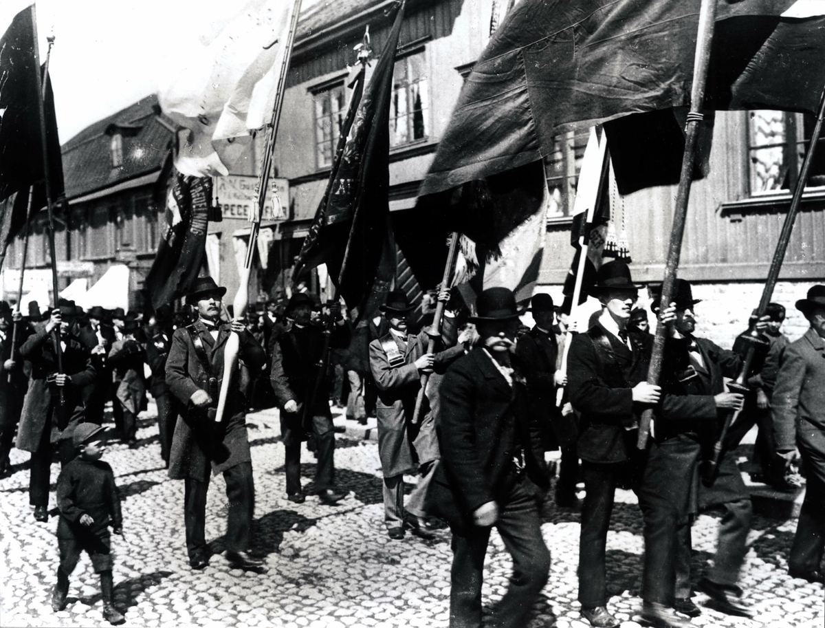 Demonstration. Stockholm, 1:a maj 1902. Män i demonstrationståg med fanor.