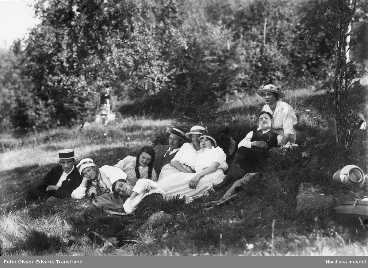 "Där man mår som pärla i guld." Sommarklädda ungdomar vilar i gräset i en skogsbacke. Dalarna, Lima / Transtrand socken.