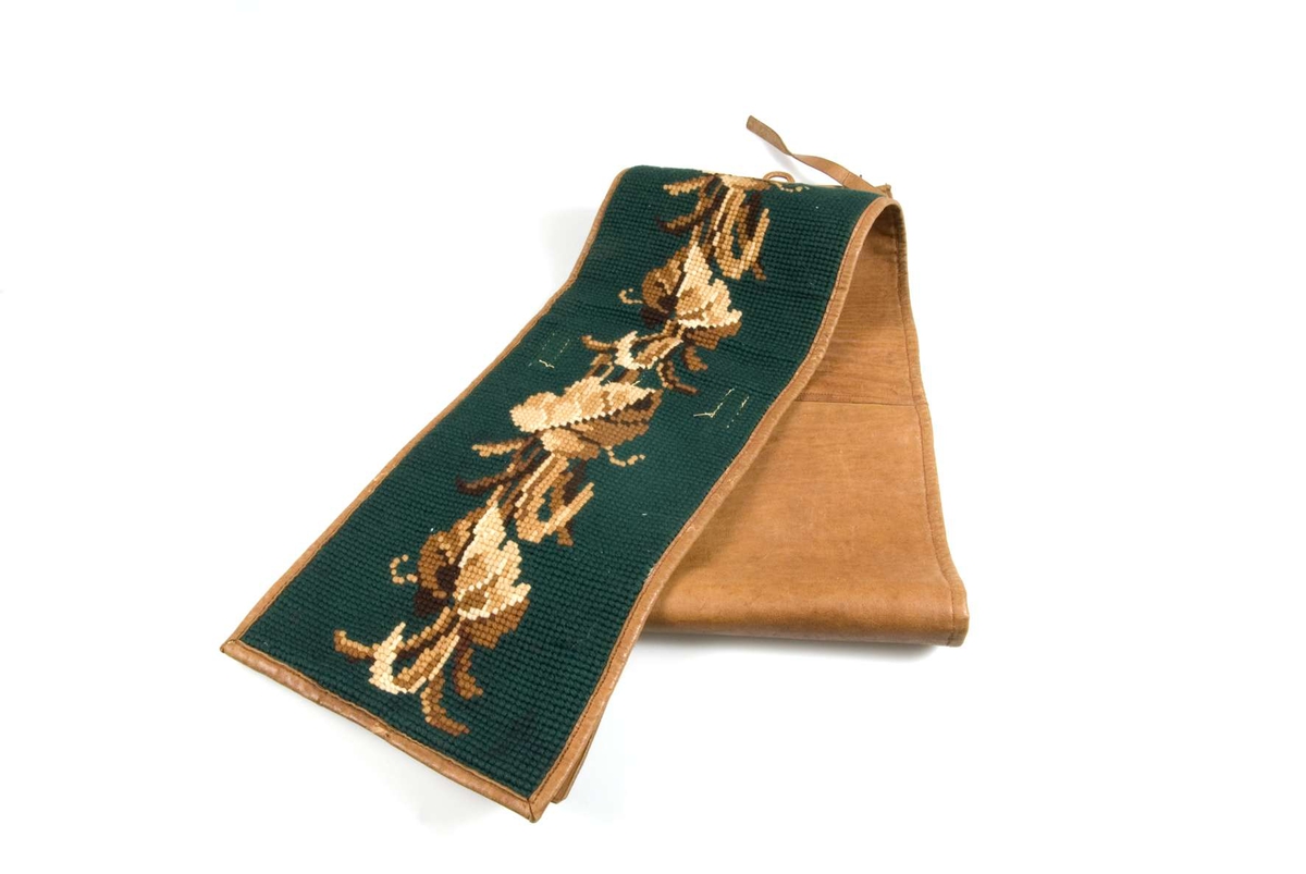 Resskärp av läder med korsstygnsbroderi i ullgarn i brunt och grönt.