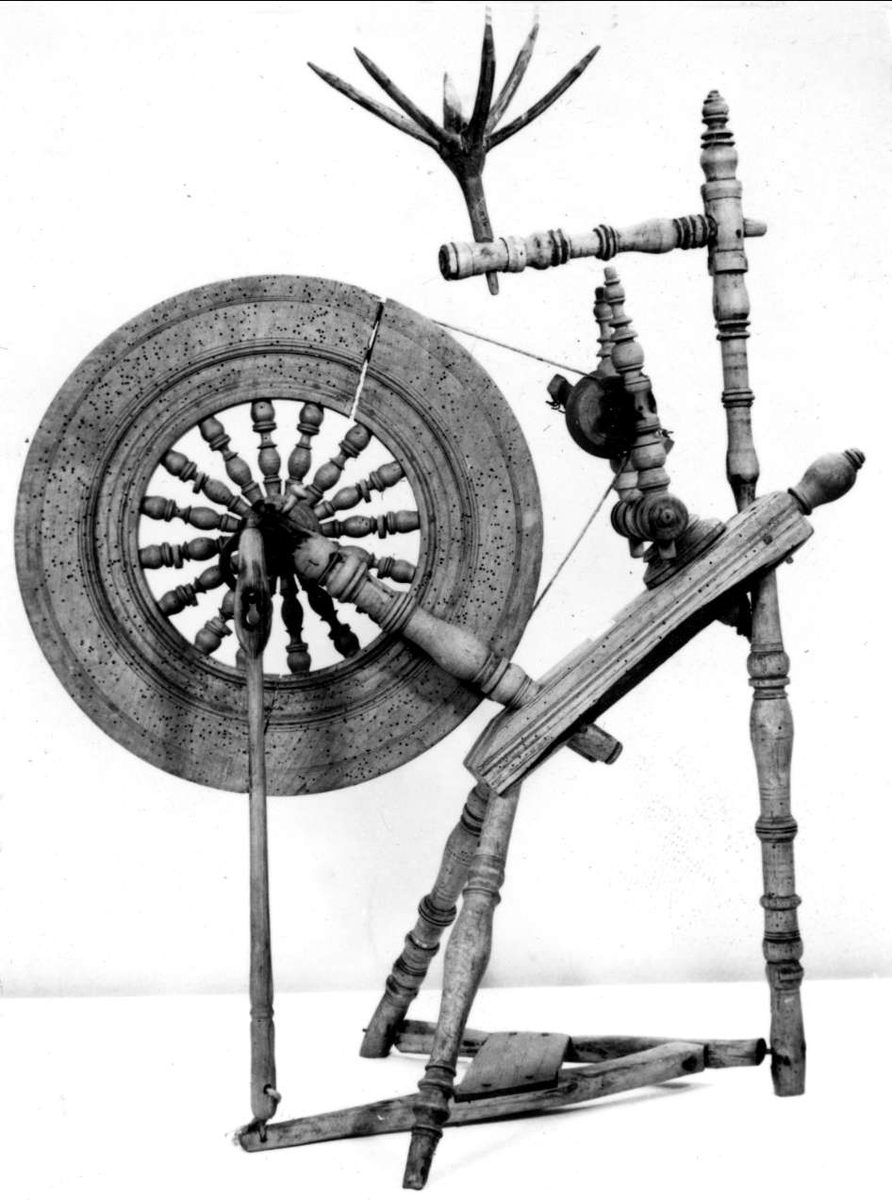 Spinnrock med tovklyka. Av trä de flesta delarna svarvade. Hjulet massivt med korta pinnar. 