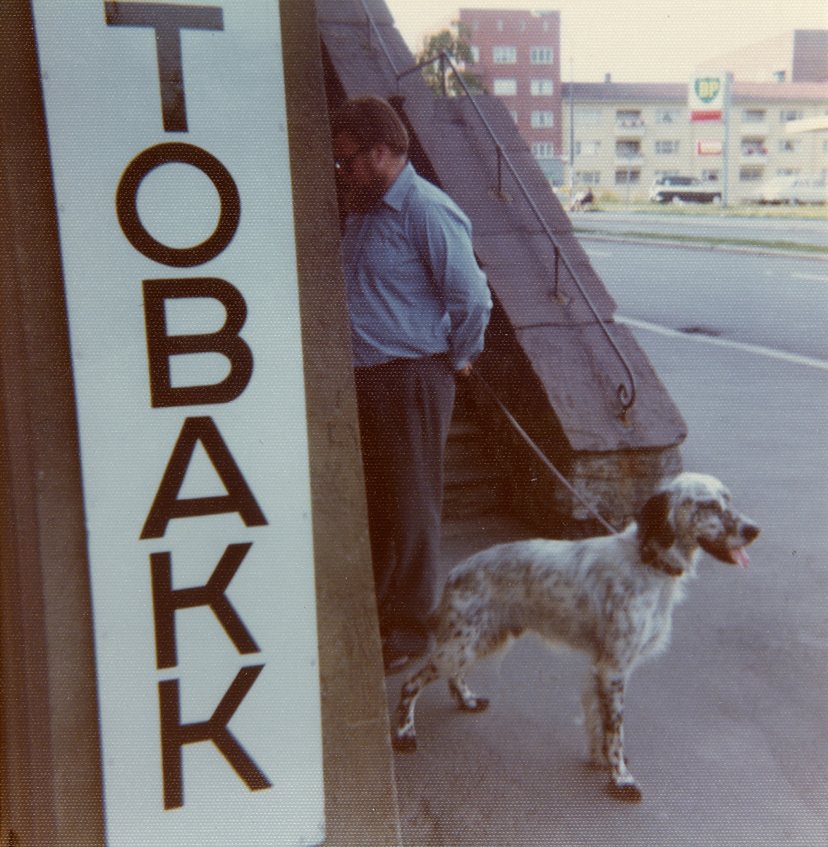 Mann med hund ved tobakk-skilt.