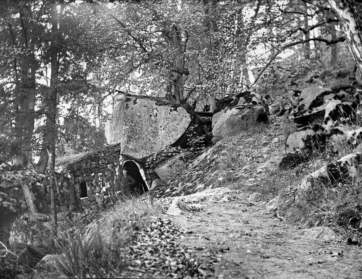 Man i öppningen till Kettils grotta i Rosersbergs slottspark, Norrsunda socken, Uppland oktober 1911