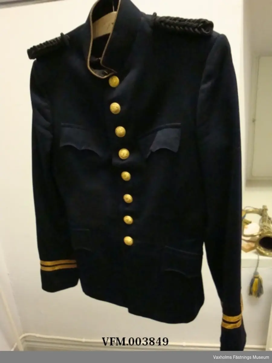 Uniform, kolett och byxor i blått kläde m/02, med löjtnants gradbeteckning. På höger ärm flygtecken m/15 (flygspanare)