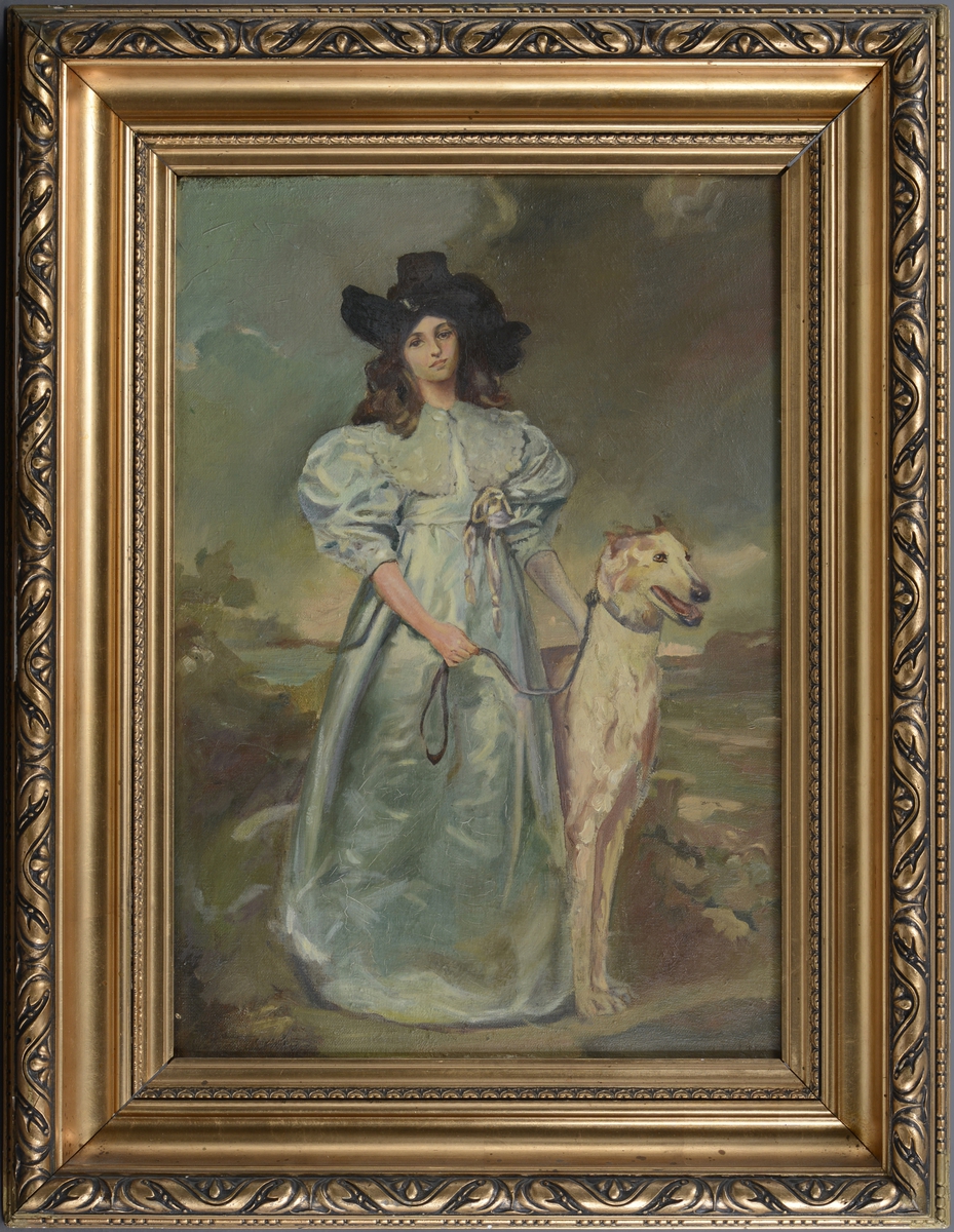 En kvinne med hund i bånd står i et landskap.