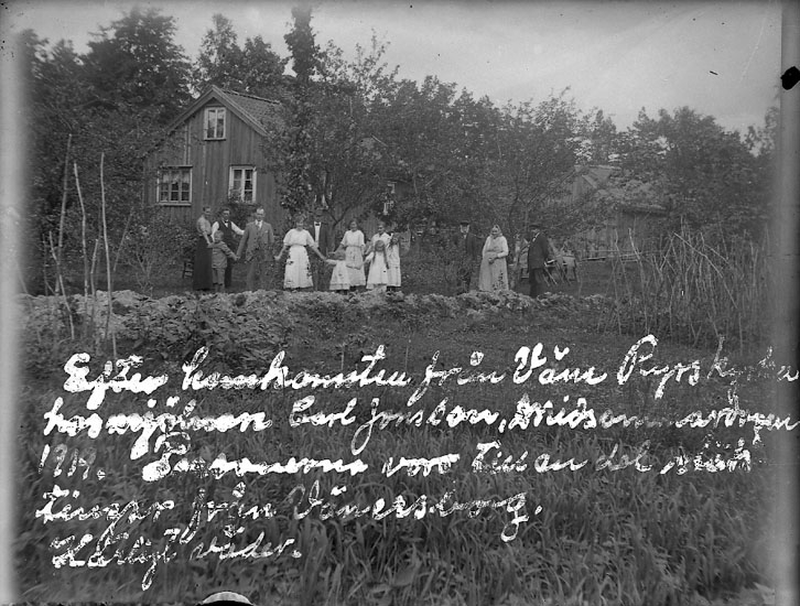 Enligt text på fotot: "Efter hemkomsten från Väne Ryrs kyrka hos mjölnaren Carl Jonsson, Midsommardagen 1919. Personerna var till en del släktingar från Vänersborg. Härligt väder".