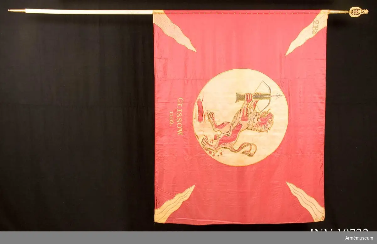 Grupp B.

Utdelad till regementet 1866. Duken är av rött siden med gula flammor i hörnen. På mitten ett gult fält med det uppresta lejonet som i tassarna håller ett uppspännt armborst. Under cirkeln broderat: Clissow 1702.