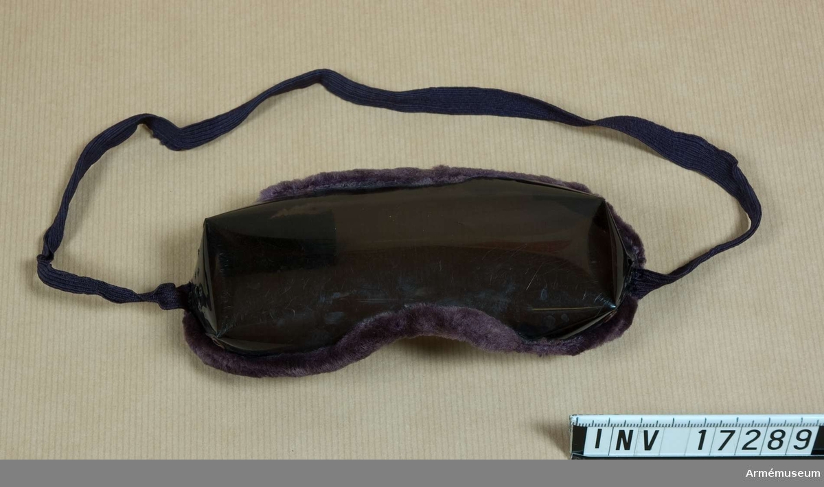 Grupp C II.
Solglasögon av celluloid i violett färg. Specialtyg omkring celluloiden och gummiband.