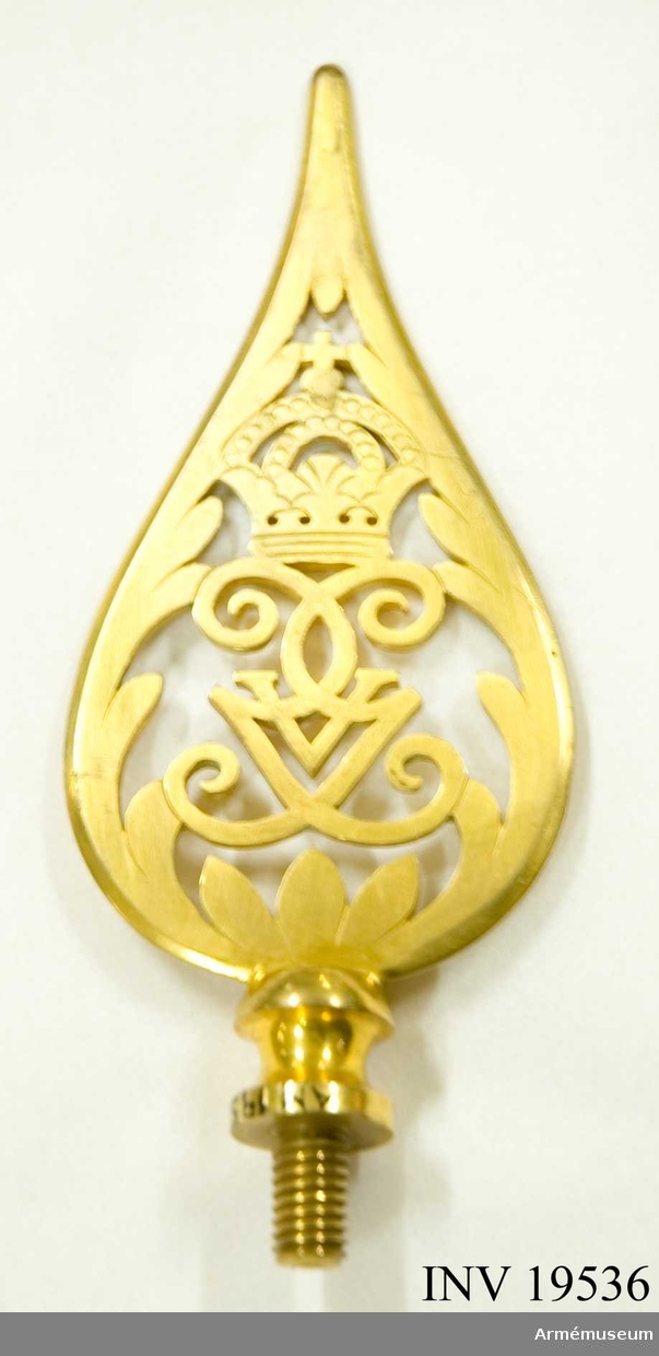 Spetsen är tillverkad av förgylld mässing. Den har Gustav V:s spegelmonogram under en kunglig krona inramat av ett bladverk avslutas i en spets. Spetsen försedd med en skruv.