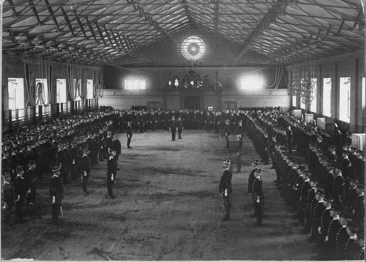 Göta livgardes, I 2, avlämning i april 1896. Den avgående sekundchefen generalmajor J. Z. Rudbeck avtackar och den pågående överste P.C.L. Lovén avlämnar regementet i dess gymnastiksal.
