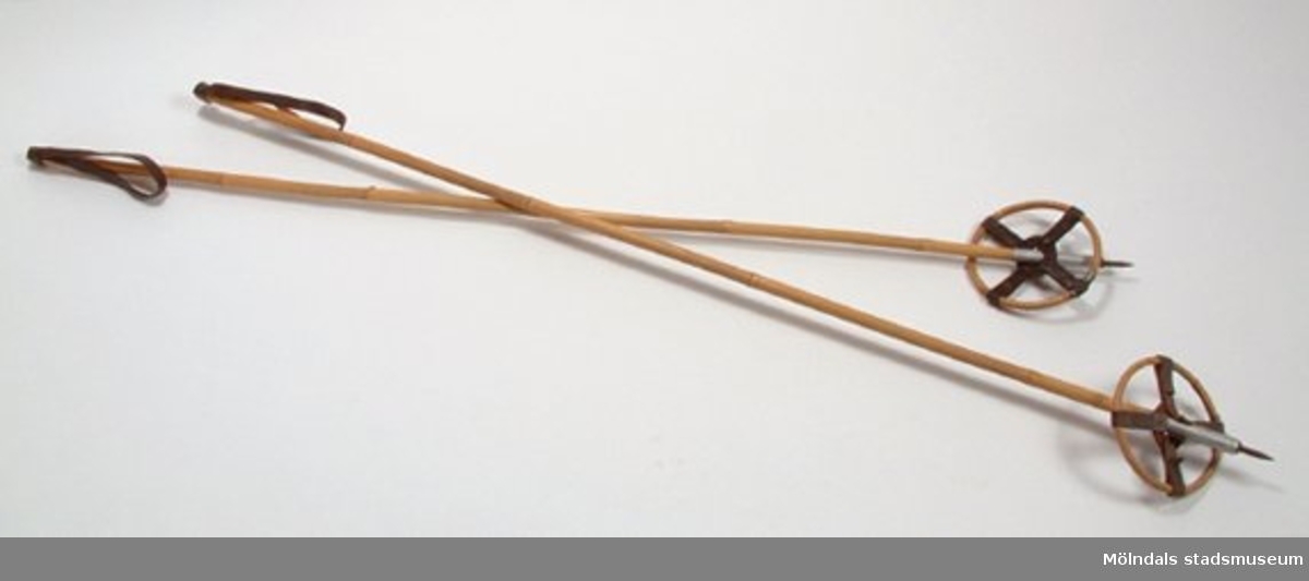 Stav och tryga (ring nertill på staven, som förhindrar att staven sjunker ner i snön) av bambu, metallbrodd, läderremmar. Troligen från 1930-talet. Hör ihop med skidor, Mölndals museums föremålsnummer 00009.