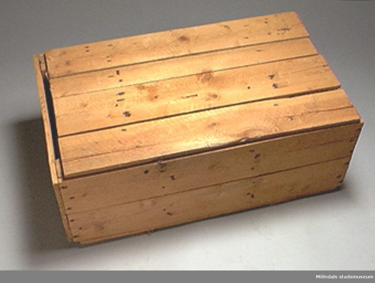 Låda med diverse tyglappar (tygprover) som förvaras ståendes och ihoprullade i lådans tre fack.