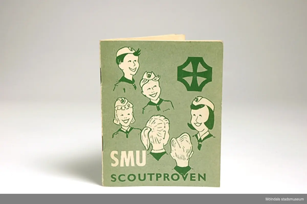 Ett grönt litet häfte "SMU scoutproven" utgivet av Missionsförbundets förlag. Pris 50 öre står på baksidan. Framsidan har bilder av pojk- och flickscouter. Inne i boken står ägarens namn, namnen på patrullkamrater och ledare, regler, proven och provtagningstillfällen m.m.Givaren/ägaren gick med i SMU-scouterna 1956 nio år gammal. Man samlades i Missionskyrkan i Kållered 1 gång/vecka. Gruppen bestod av enbart flickor. Det var en speciell tillhörighetskänsla att vara scout. Ledaren hette Lotta. Givaren åkte även på lägerveckor i Sjövik vid sjön Anten.