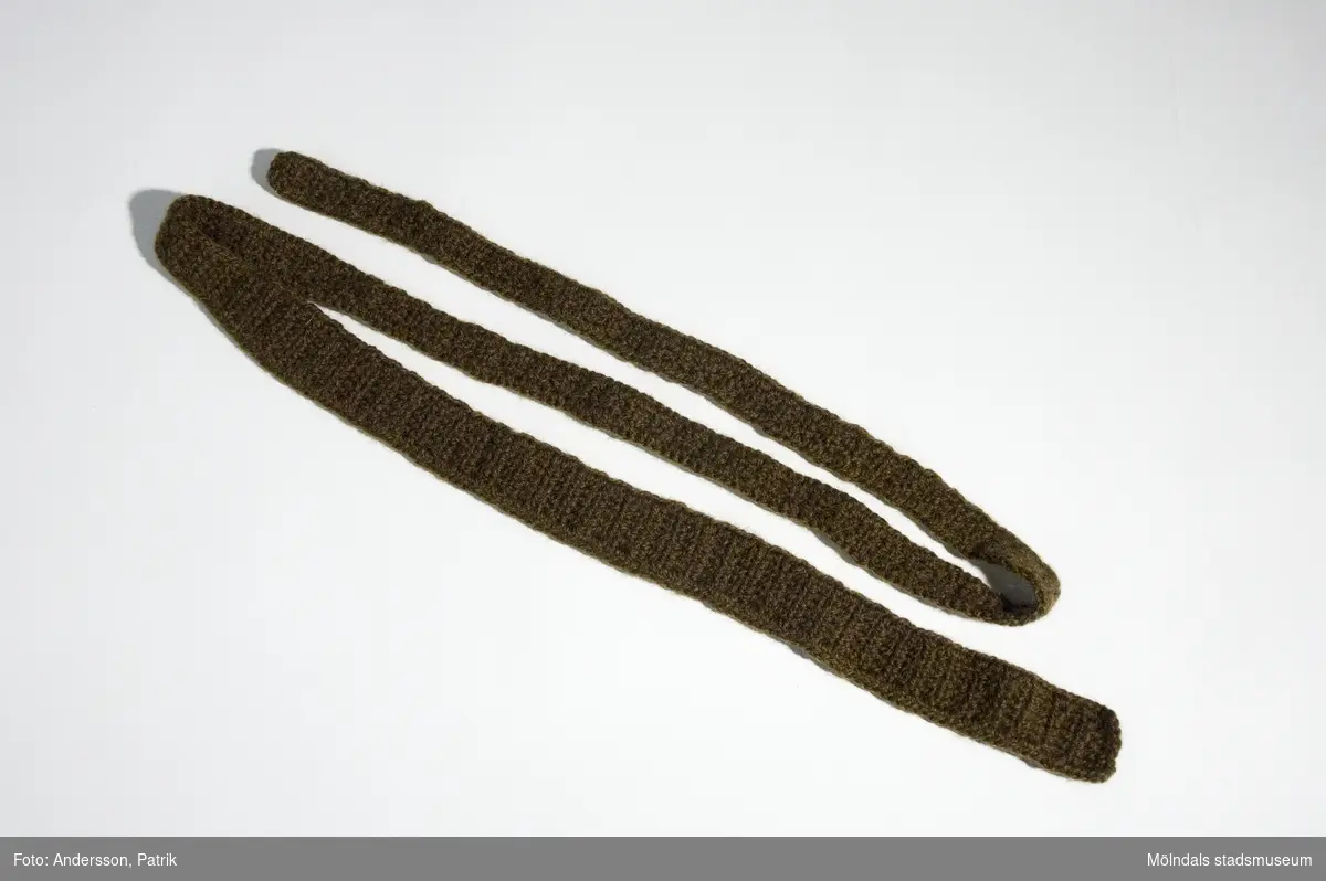 Mossgrön virkad slips från cirka 1970-talet. Slipsen virkade givaren Kerstin Olofsson till sig själv.MåttLängd: cirka 1370 mm, Bredd: cirka 35 mm.
