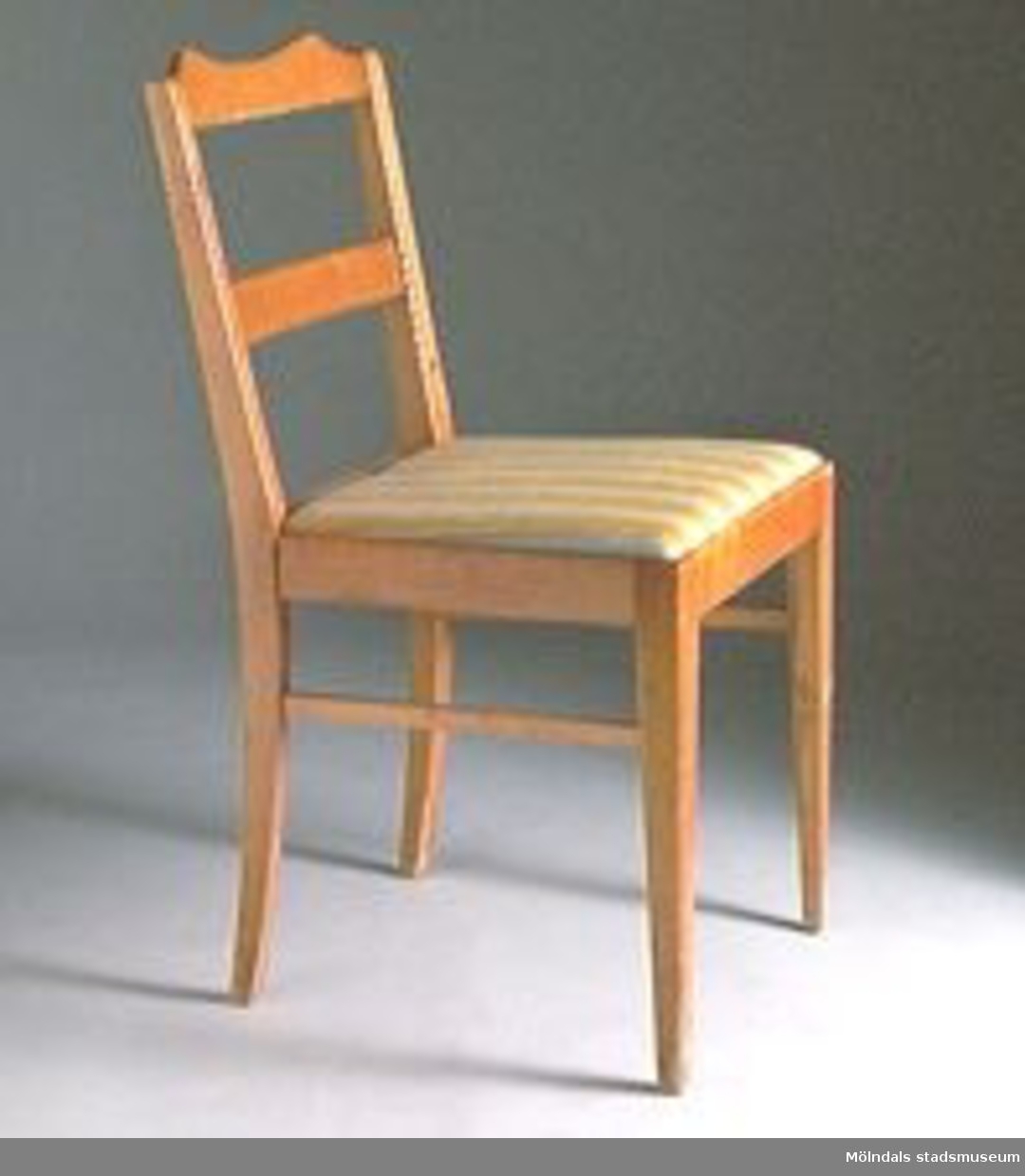 Stol med rygg (två vågräta brädor). R03115:1 Sitsen lös och klädd med tyg som har gula och gråa ränder (f.d MM01912:1). 
R0315:2 En stol är oklädd. Den stolen har fast och lackad träsits (f.d. MM01912:4).

Stol MM01912:3-4 utgallrade 2002-01-17. Överförda till rekvisita R03115:1-2.