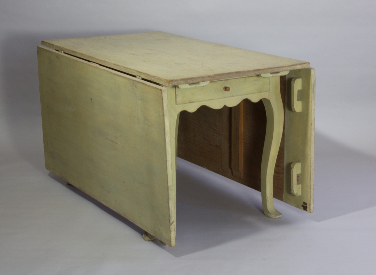 Slagbord av målat trä med två uppfällbara flygelskivor och med svängda ben med profilerade avslut. Sarg med lådor.