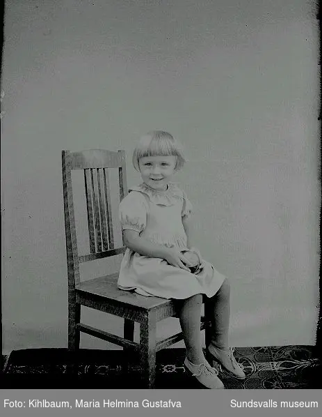 Porträtt, flicka sitter på stol.