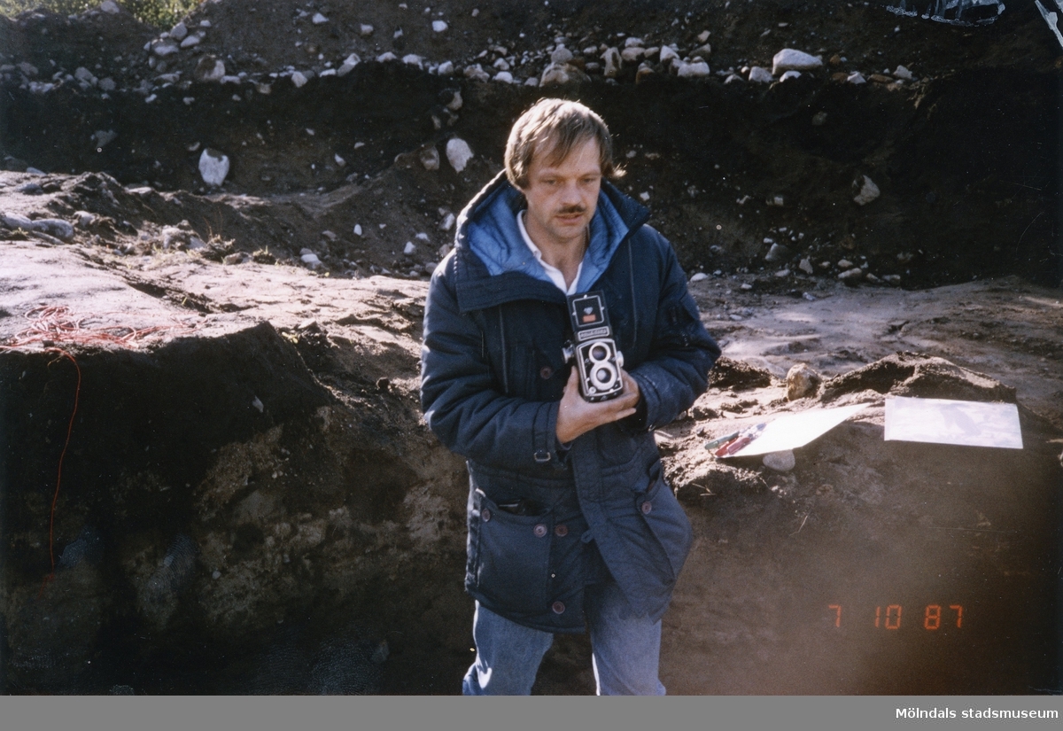Bengt Nordqvist vid en utgrävning med en kamera i handen. Bilden är troligtvis tagen i Balltorp 1987.