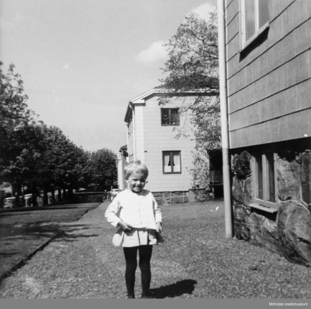 En liten flicka som står utanför papyrushusen på Brunnsgatan (1-9). 1960-tal.