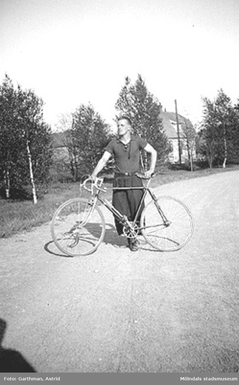 Helmer Garthman står på en grusväg bredvid sin cykel. Fjärås Bräcka, 1930-tal.