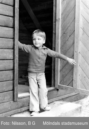 En pojke som står i ingången till ett förrådshus. Holtermanska daghemmet 1973.