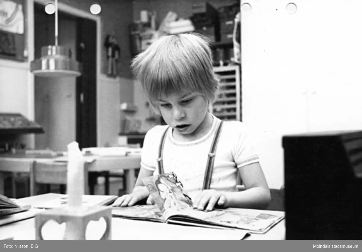 Ett barn som tittar i en bilderbok. Holtermanska daghemmet maj 1975.
