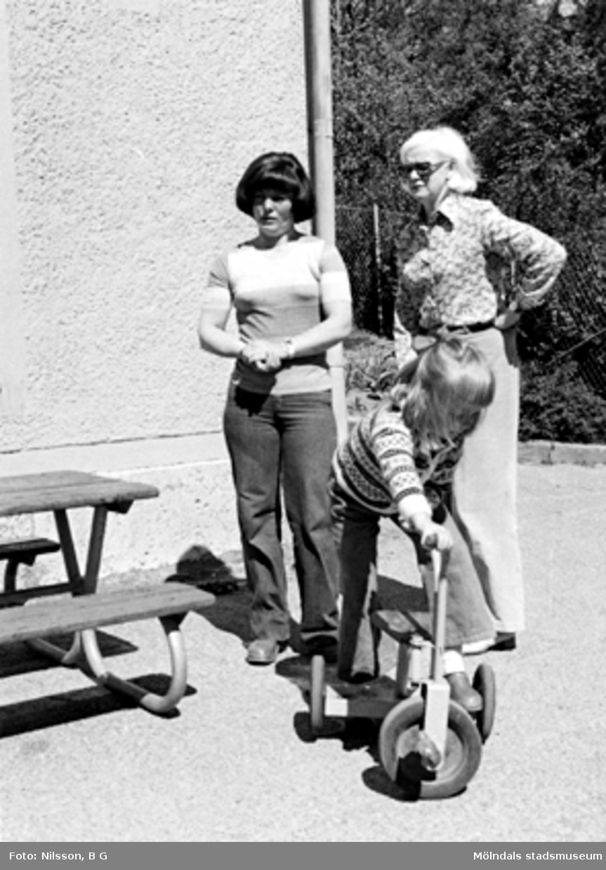 Ett barn på en cykel och två fröknar. Holtermanska daghemmet, okänt årtal.