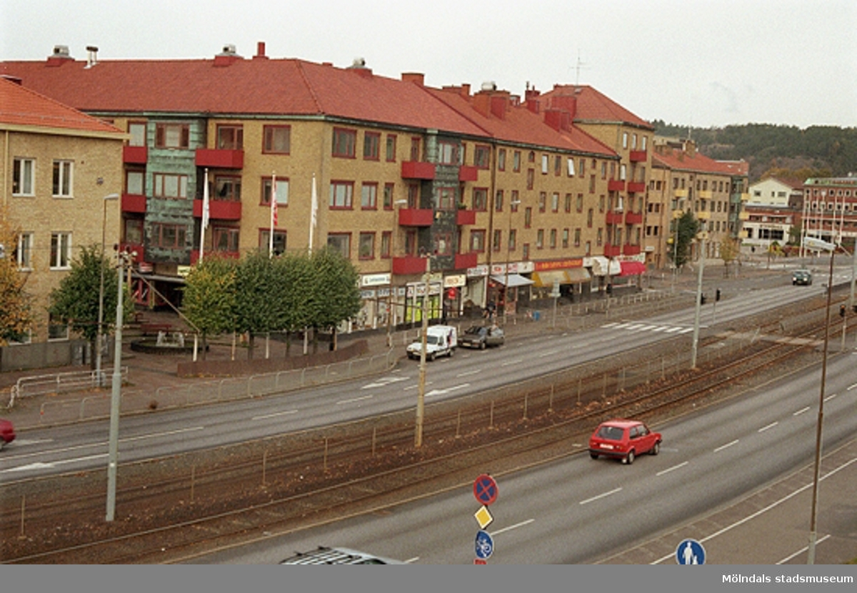 Vy från bron över spårvagnsspåren samt Göteborgsvägen. Folkets hus skymtar till höger. Mölndalsbro i dag - ett skolpedagogiskt dokumentationsprojekt på Mölndals museum under oktober 1996. 1996_1301-1319 är gjorda av högstadieelever från Åbyskolan 8A, grupp 4. Se även 1996_0913-0940, gruppbilder på klasserna 1996_1382-1405 och bilder från den färdiga utställningen 1996_1358-1381.