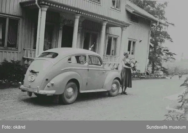 Greta Bolin på gårdsplanen framför platschefsbostad nr 2 vid Nensjö cellulosa fabrik.  Detta hus byggdes som kontor till Sprängsvikens sågverk.Platschefsbostad nr 1 var ombyggd till mäss och kallades Nensjögården. Bilen är familjens Ford Taunus, 1950 års modell.