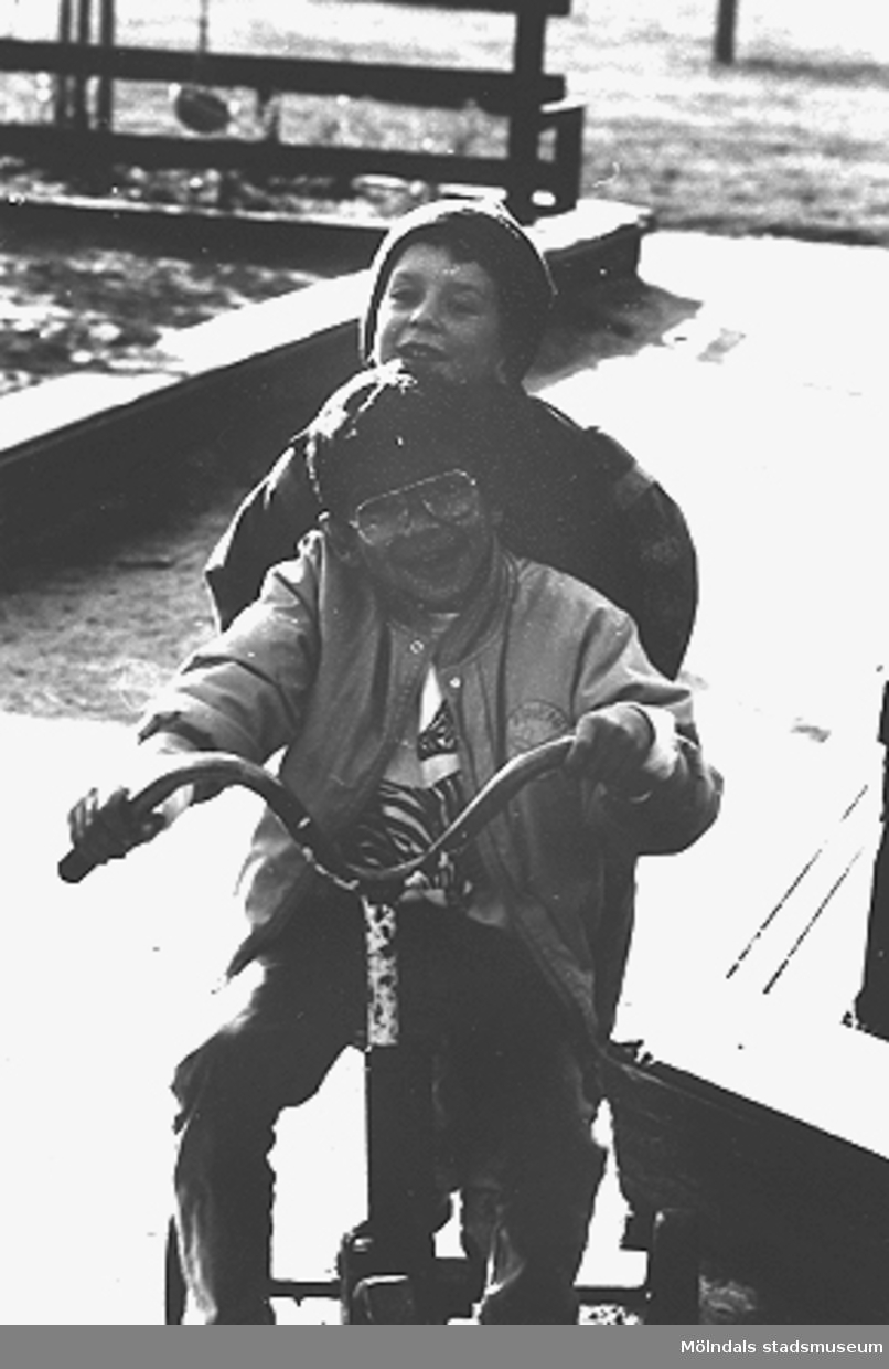 Främst sitter Jarmin Abdagalil och bakom honom sitter Andreas Carlsson. Bifrosts daghems lekplats, hösten 1987.