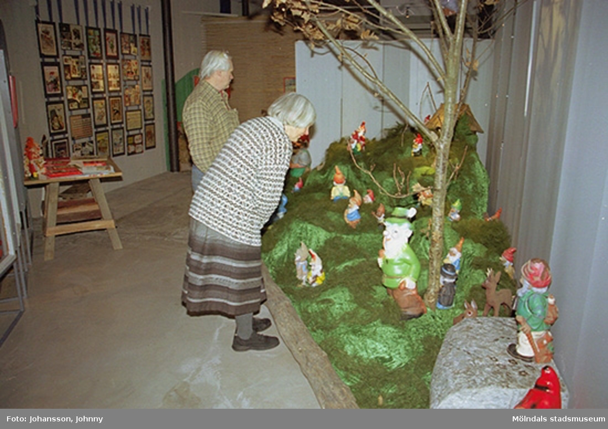 Invigningen på Mölndals museum 2002-11-30.
Besökare som tittar på trädgårdstomtar.
Tomteutställningen: 30/11-02 - 1/1-03.