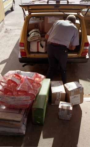 Lantbrevbärare Reinhold Andersson paketerar utgående post i postbil
vid en postanstalts lastkaj. Tillhör en dokumentation av en
lantbrevbärare i trakten av Valdermarsvik av fotograf Ove Kaneberg.