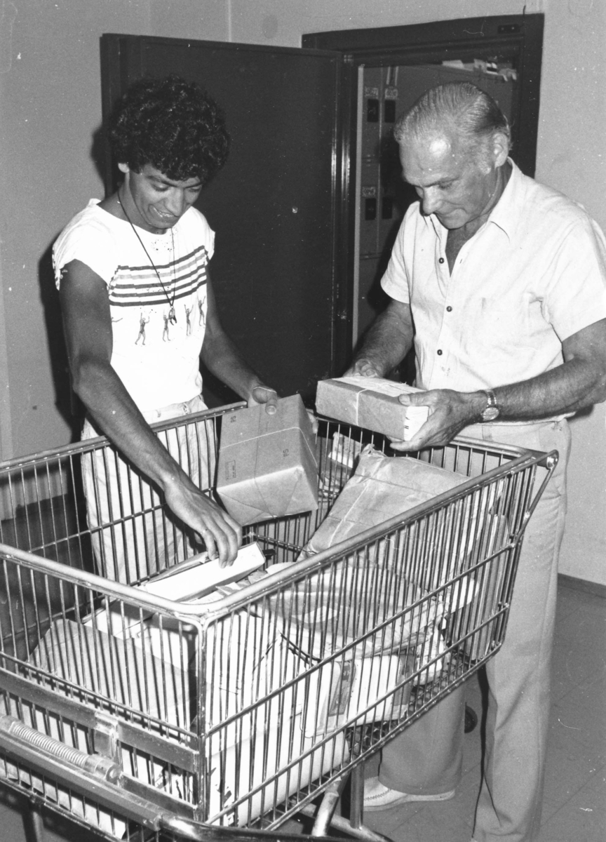 Postkassörselev Hassan Esteka och postmästare Gösta Eriksson hjälps åt på postkontoret Spånga 4, 1982.