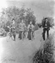 Fire personer ute på sykkeltur, på landeveien, trær i bakgru