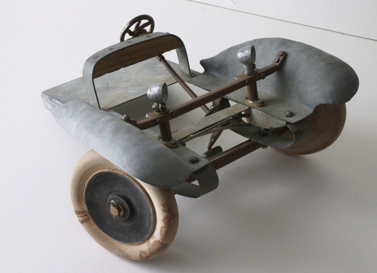 Selve bilen er laget av blikk og messing. Hjulene er laget av gummi. Hans Edwardsen, Homme laget denne modellen og sendte den til Henry Ford, Detroit, Michigan, U.S.America. Denne bilen viser en unik styrings-mekanisme, samtidig som lyktene beveger seg etter styringen. 