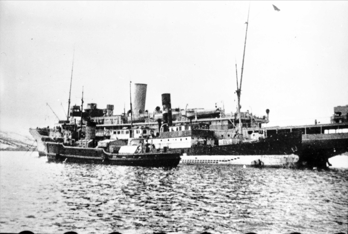 M/s "Stella Polaris" i bakgrunnen, to  mindre fartøyer og én ubåt ligger ved siden av.