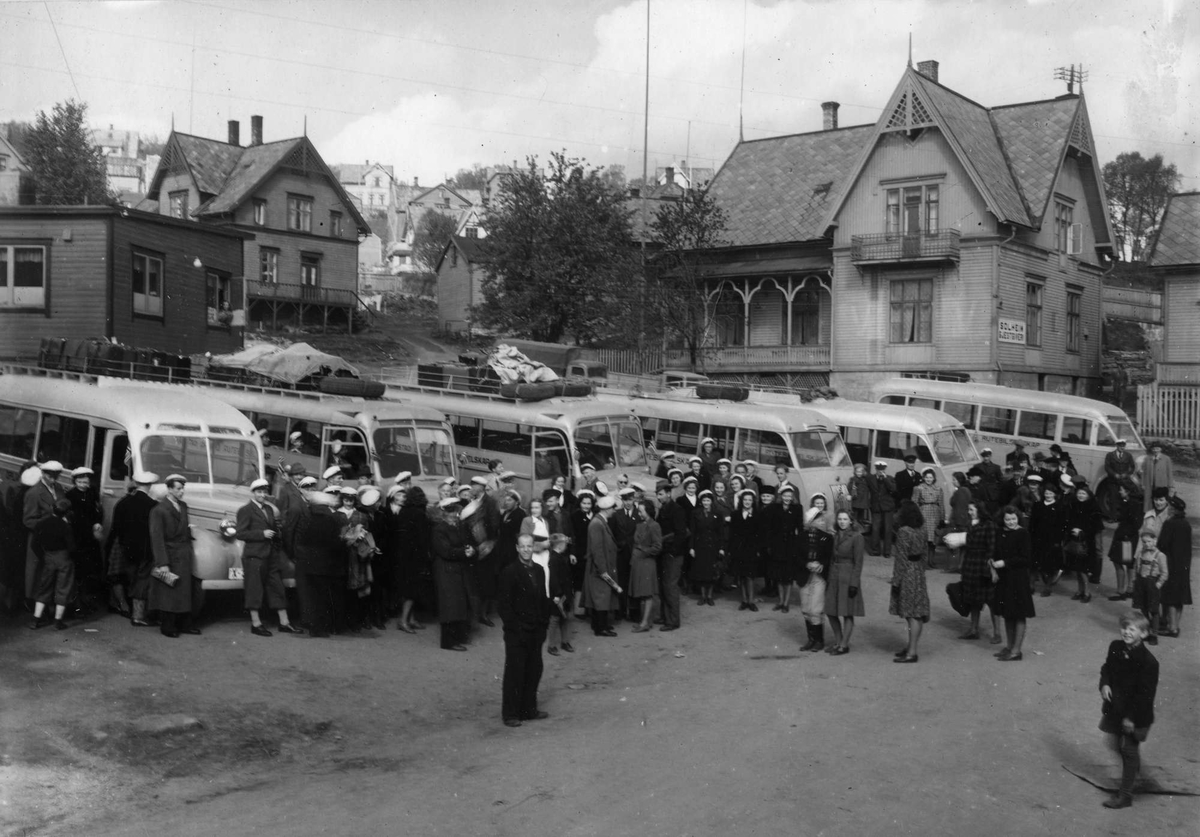 Sangkor foran oppstilte busser på den gamle busstasjonen i Erlingsgate. Solheim pensjonat i bakgrunnen.