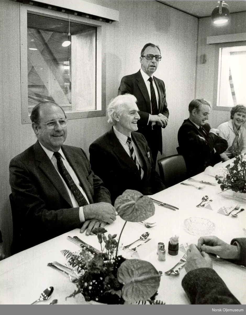 Fra åpningen av Nord-Øst Frigg i 1988.  Konrad B. Knudsen holder tale, mens tidligere olje- og energiminister  Kåre Kristiansen sitter ved hans høyre side.  Kristin Lønningdal sees ved enden av bordet.
