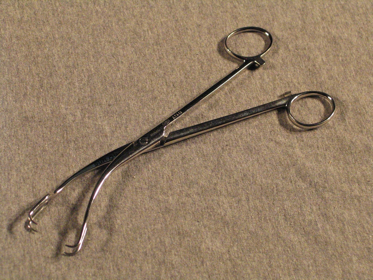 Forma som ei tang med låsbart skaft. Fremste delen  er krumma og begge nebba forma som totinda gaffel.