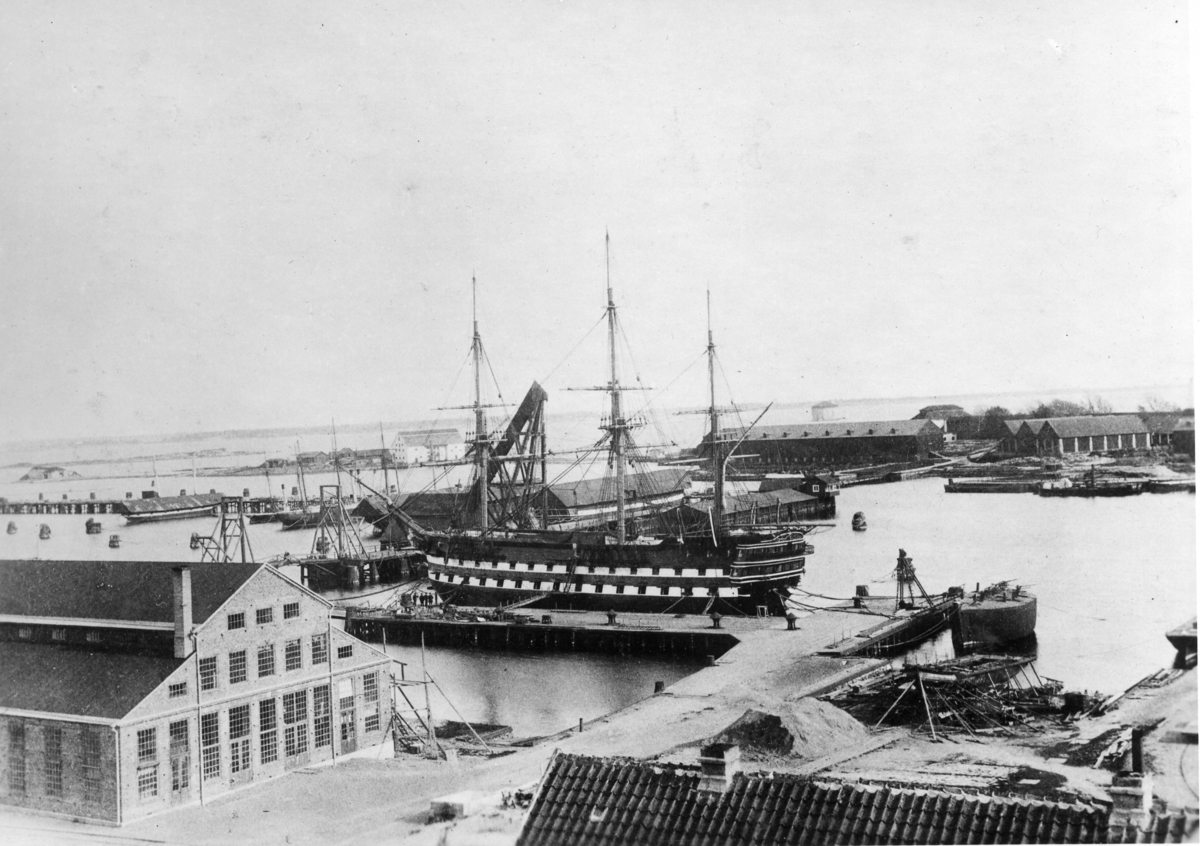 Bilden visar linjeskeppet Stockholm vid kölhalningsbron i Karlskrona. Till vänster ser man den nya uppförda tackelkammaren. Bakom linjeskeppet syns mastkranen från 1728 och en klaffbro. Bilden är tagen från varvsmuseets gamla lokal modellkammaren år 1884.