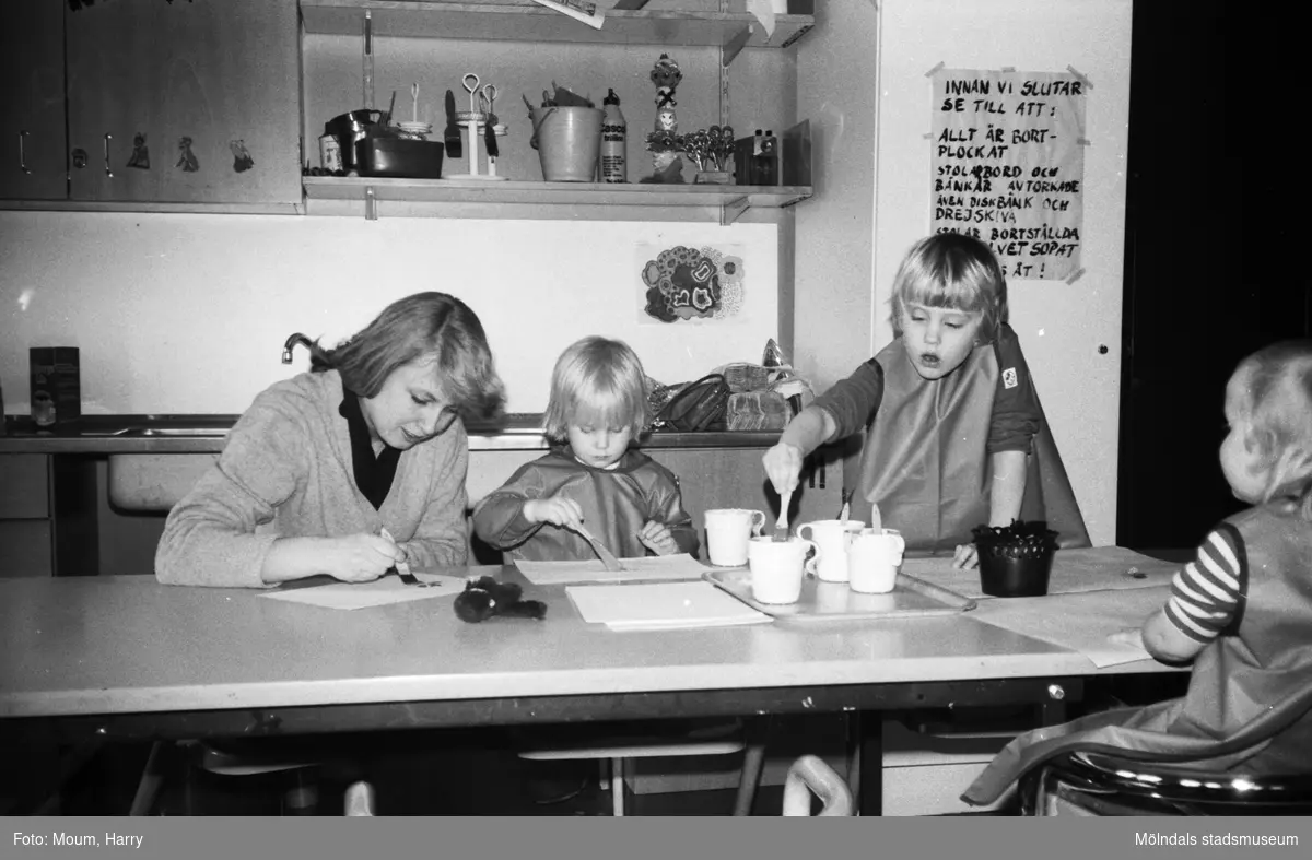 Öppen förskola på Almåsgården i Lindome, år 1983. Kvinna och barn sitter och målar.

För mer information om bilden se under tilläggsinformation.