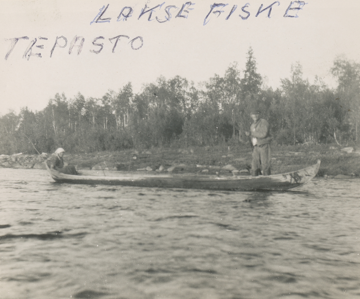 En mann og kvinne i en elvebåt ved Tepasto i Finland. Mannen står og fisker etter laks.