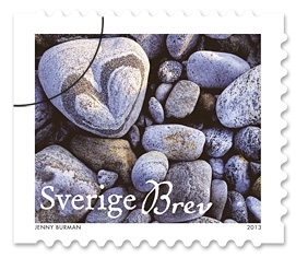 Ett frimärke i häfte med stenar från stranden i blå och grå färger. En sten med motiv av ett hjärta.
Valör inrikes brev, 6 kr.