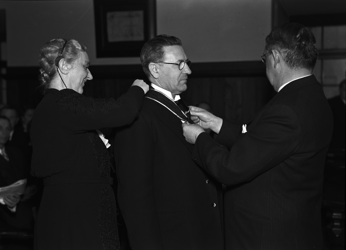 Man får medalj av landshövding Hilding Kjellman, med assistans av kvinna. Uppsala i april 1945