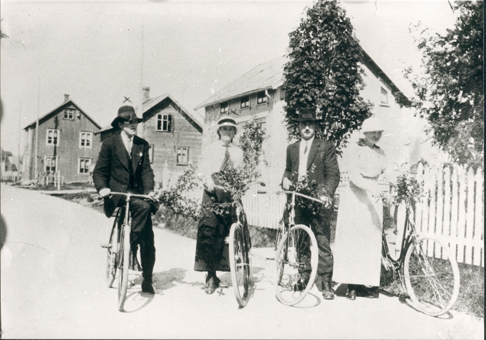 Gatemotiv Toraneset/strandgata. To unge damer og to unge menn m/sykler. Fra venstre : Sverre Fiskum, Olga Olsen, Aksel Høines, og Agneta Torp. Huset i bakgrunnen til venstre som skimtes såvidt, er Aksel Jakobsens hus hvor veien svinger til høyre mot vika. Vår eller sommer.