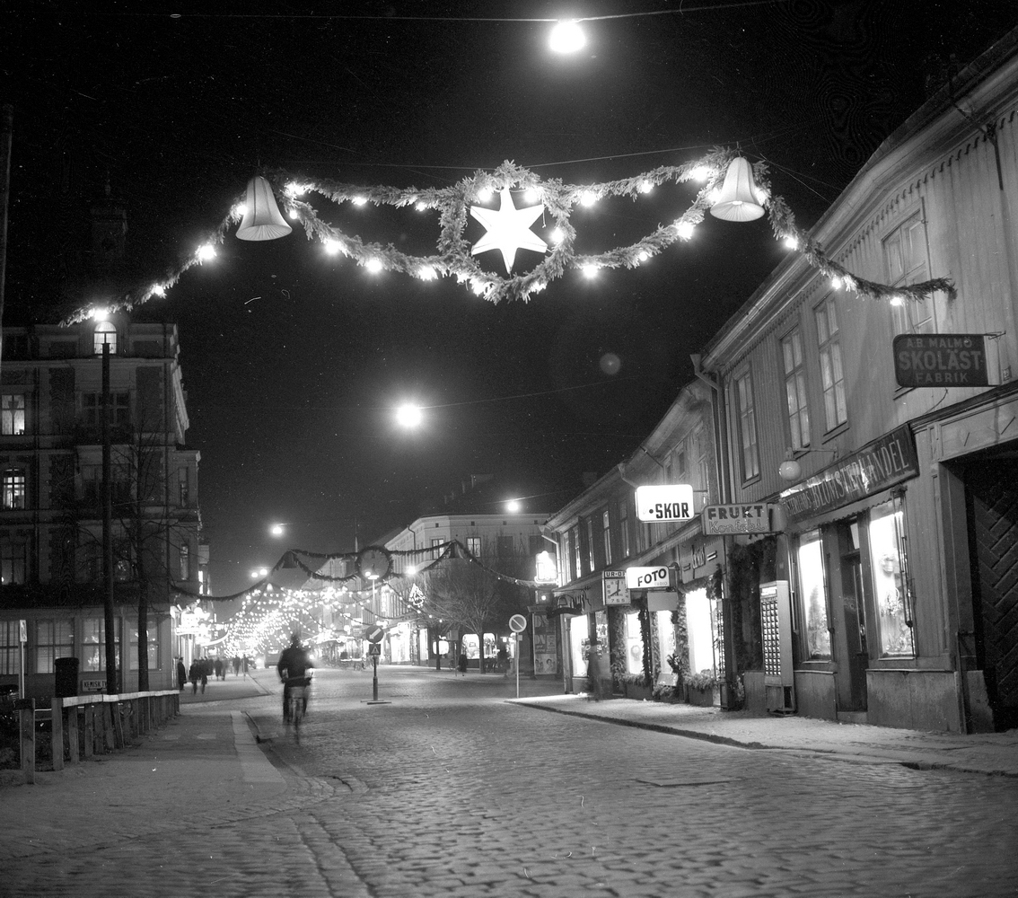 Julbildssidan.
24 december 1954. 
Drottninggatan norrut med gamla Krämarkvarteret Drottninggatan 27 till höger och hörnhuset Drottninggatan 36/Rudbecksgatan 21 till vänster. Lite längre bort på höger sida Våghustorget.