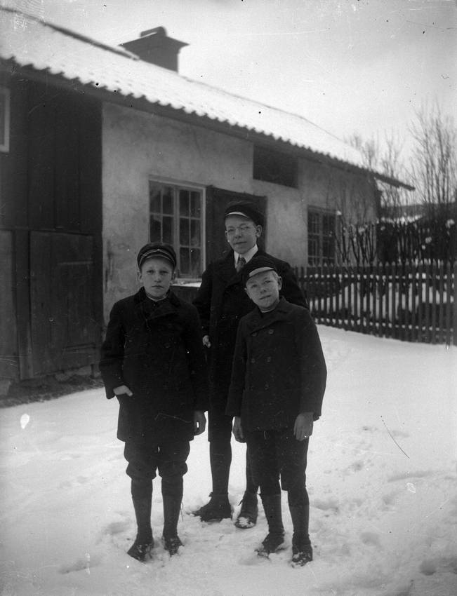 Tre pojkar. Bostadshus i bakgrunden.
Till vänster Harald Pettersson (givarens pappa), övriga ej namngivna.