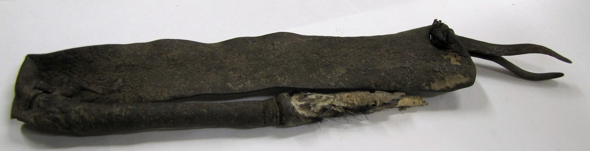 Pincett av metall i en lädergrej. Längd: 7 cm. Möjligen från Ovambo, Namibia? Bricka: Ä.

Föremålet tillhör den etnografiska samlingen.
