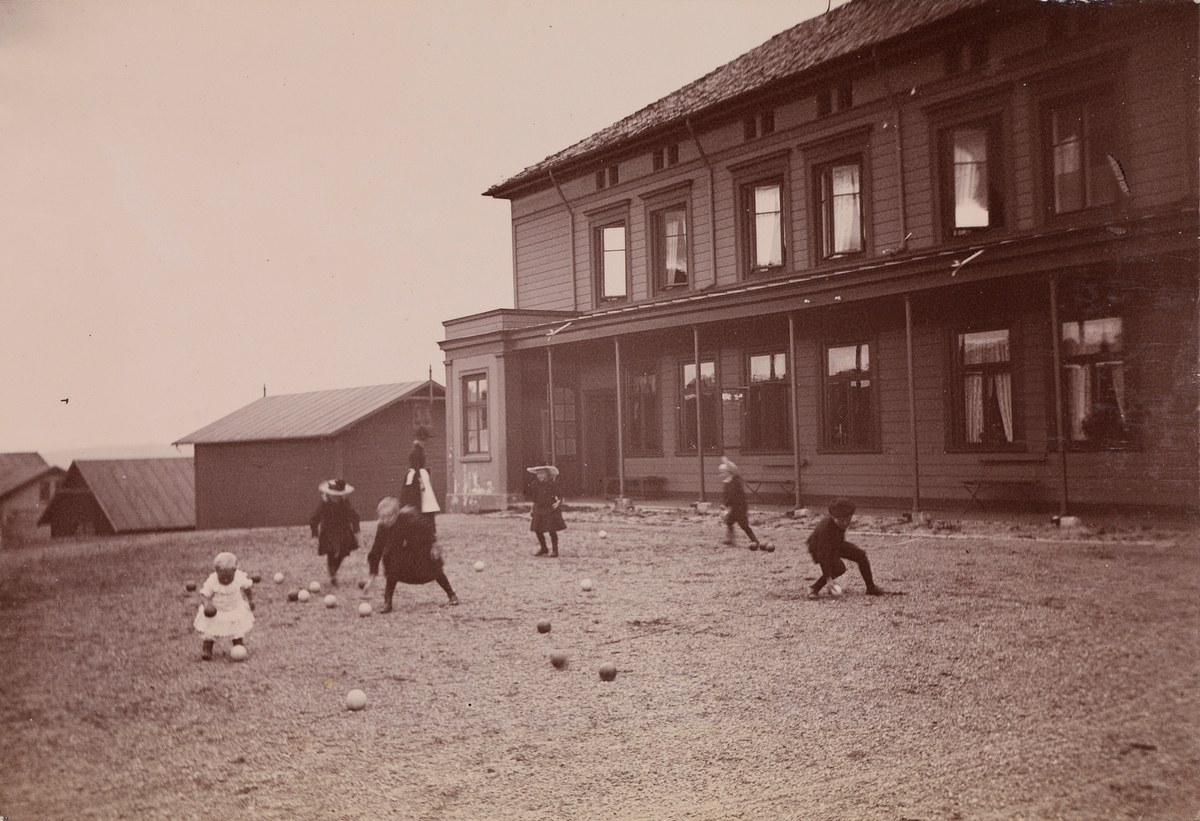 Christensen-barna spiller Boccia foran Linderud Gård hovedhus. I bakgrunnen ei kvinne.